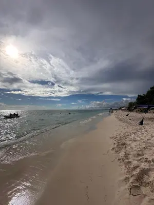 a sandy beach with people swimming in the ocean at D&L Apartment in Bayahibe