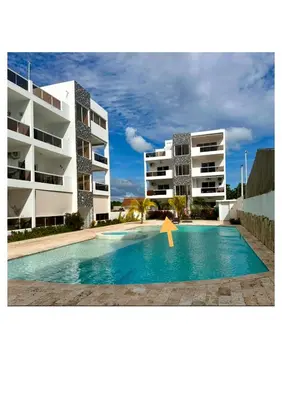 a swimming pool in front of two apartment buildings at D&L Apartment in Bayahibe