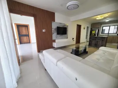 a living room with a white couch and a tv at Cama king, piscina 3 habitacines in Santiago de los Caballeros