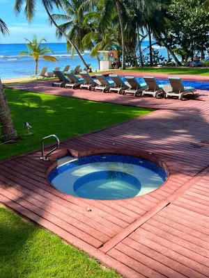 a swimming pool with chairs and a table and the ocean at Aqua Loft 120 in La Puntica de Juan Dolio