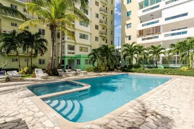 a swimming pool in front of a building with palm trees at Luxury Ocean View Condo in Santo Domingo in La Francia