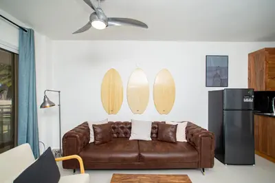 a living room with a brown couch and surfboards on the wall at CMB202 BEACH AREA Res Cristamar in Eslabón