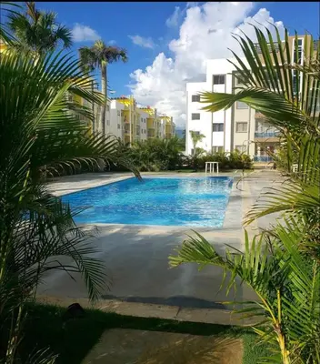 a swimming pool with palm trees and buildings at Cozy Retreat 1st Floor in Arenoso