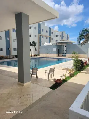 a swimming pool with two chairs next to a building at Romana Tropical in La Romana