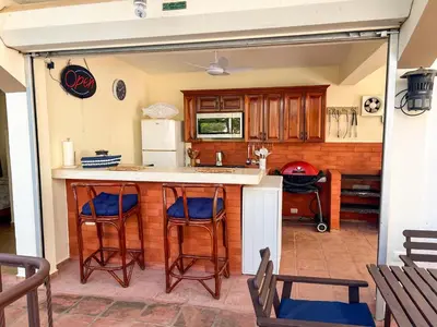 a kitchen with a bar with blue stools at Villa Cruz in Las Galeras
