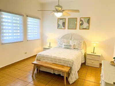a bedroom with a bed and two tables and two windows at Villa Cruz in Las Galeras