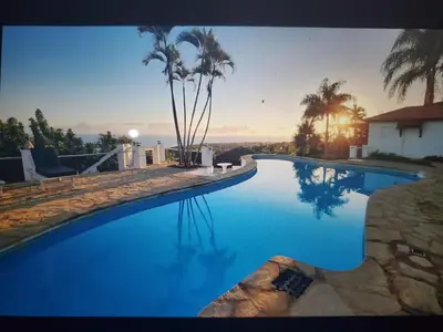 a large swimming pool with blue water and palm trees at Villa Los Corralillos in Cabrera