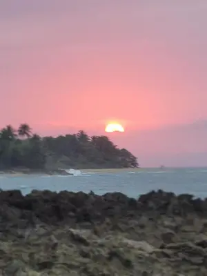 a sunset over a body of water with a island at Blue fish apartamento in Sosúa