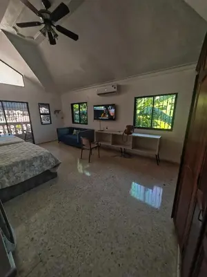 a bedroom with a bed and a desk and windows at Habitación cuádruple Casa Grande Corales del Sur in La Viva