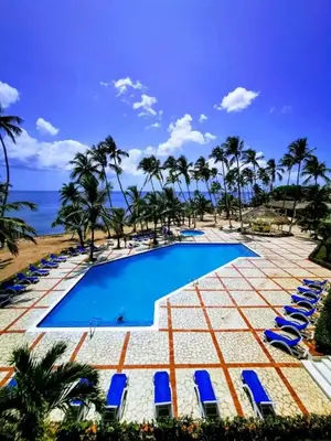 a pool with chairs and palm trees and the ocean at OCEANPARADISE to you ALBATRO l Y ll in Juan Dolio