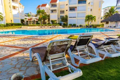 two lounge chairs in front of a swimming pool at OCEANPARADISE to you ALBATRO l Y ll in Juan Dolio