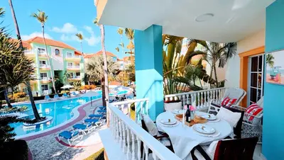 a balcony with a table and chairs next to a pool at Walk to Beach, Shops, Dining, Pool View, Fast Wifi in Punta Cana