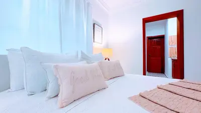 a white bed with white pillows and a red door at Walk to Beach, Shops, Dining, Pool View, Fast Wifi in Punta Cana