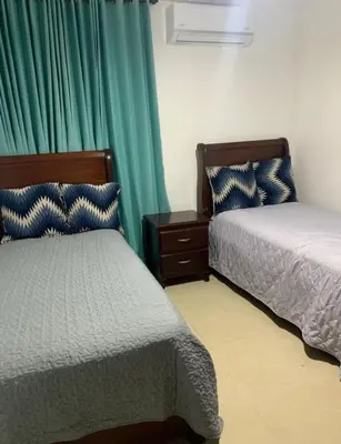 a bedroom with two beds and a green curtain at Encantadora Casa Familiar en Santiago in Santiago de los Caballeros