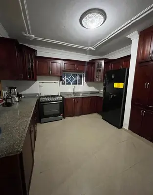 a kitchen with wooden cabinets and a black refrigerator at Encantadora Casa Familiar en Santiago in Santiago de los Caballeros