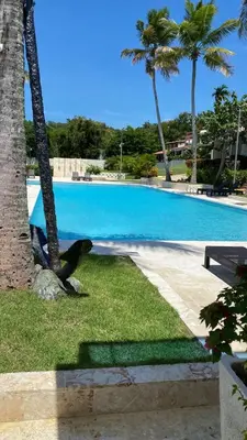 a large swimming pool with palm trees and a bench at Apartamento en Proyecto Frente al Mar en Sosua in Los Altos de Jalisco