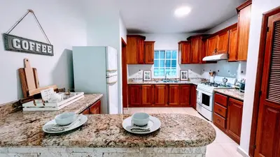 a kitchen with wooden cabinets and a marble counter top at Pool View, Walk to Beach, Shops, Dining, Fast Wifi in Punta Cana