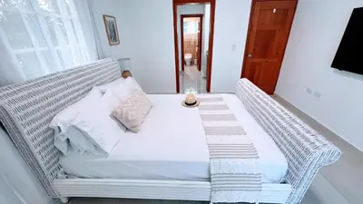 a white wicker bed in a room with a window at Pool View, Walk to Beach, Shops, Dining, Fast Wifi in Punta Cana