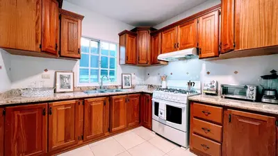 a kitchen with wooden cabinets and a white stove top oven at Pool View, Walk to Beach, Shops, Dining, Fast Wifi in Punta Cana