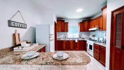 a kitchen with wooden cabinets and a coffee sign on the wall at Pool View, Walk to Beach, Shops, Dining, Fast Wifi in Punta Cana