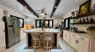 a kitchen with a refrigerator and a counter with stools at Villa Marina in Sosúa