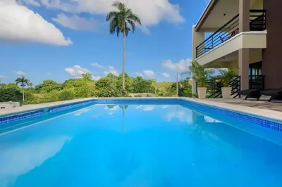 a swimming pool in front of a house with a palm tree at Casa Vista Mar in Río San Juan