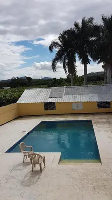 a swimming pool in front of a building with a chair at Finca im Grünen, sehr ruhige Lage, Terrasse mit Pool in Baní