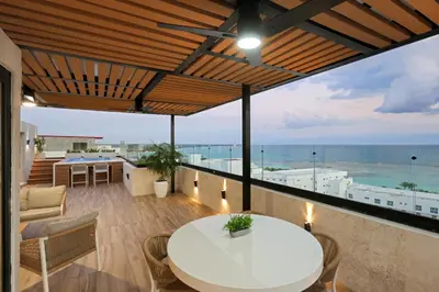 a balcony with a white table and chairs and the ocean at Lujoso Penthouse frente a la Playa de Boca Chica in Boca Chica
