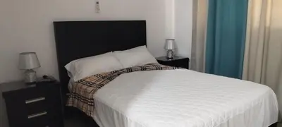 a bedroom with a bed with a black headboard and two lamps at 13 de las Americas in La Alianza