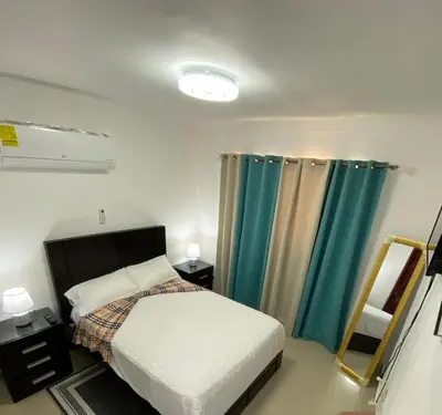 a bedroom with a bed and blue curtains and a mirror at 13 de las Americas in La Alianza