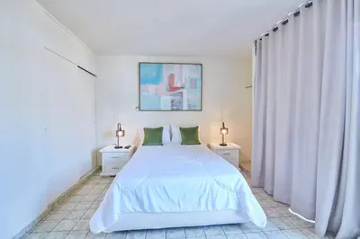 a white bedroom with a white bed and two night stands at Modern Santo Domingo Condo in Heart of Gazcue in Santo Domingo