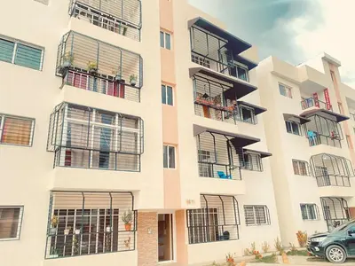 an apartment building with balconies and a car parked in front at 13 de las Américas in La Alianza