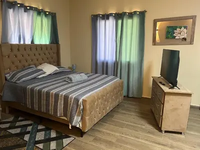a bedroom with a bed and a flat screen tv at Hostal Bless house in San Pedro de Macorís