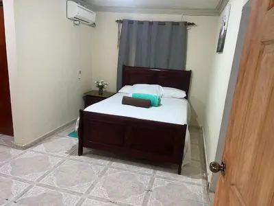a bedroom with a bed with white sheets at Hostal Bless house in San Pedro de Macorís