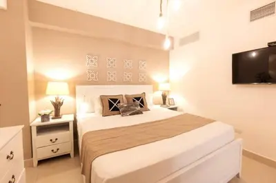 a bedroom with a large bed and a flat screen tv at Luxury Beachfront 2BR at Las Olas, Juan Dolio in La Puntica de Juan Dolio