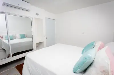 a white bedroom with a bed and a mirror at Casa Palma El Limon Samana in El Limón