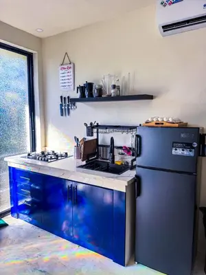 a kitchen with blue cabinets and a black refrigerator at Kaleidoscopic Apartment in La Majagua