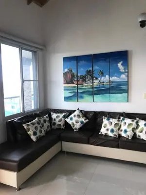 a black couch with pillows in a room with windows at casita del padre pio in Punta Rucia