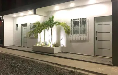 a white building with two palm trees in front of it at Bayahibe Apartments in Bayahibe