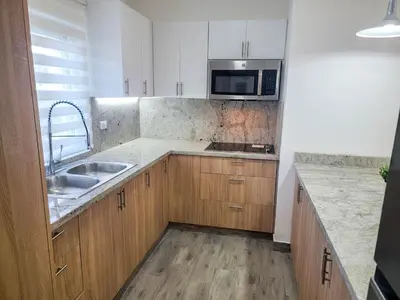 a kitchen with wooden cabinets and a sink and a microwave at Lovely Condo in Gated Community in Sosúa