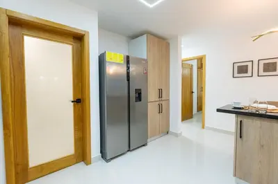 a kitchen with a refrigerator in the middle of a room at Modern 3BR! 9fl, King Bed! Sti!, in Santiago de los Caballeros