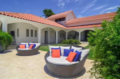 two chairs with colorful pillows on a patio at Cacique 13, Ocean View and Golf Course in La Romana