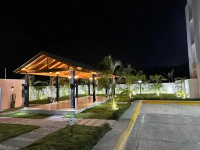 a pavilion at night with palm trees and a building at Legado Edif V Apto A2 in Azua de Compostela