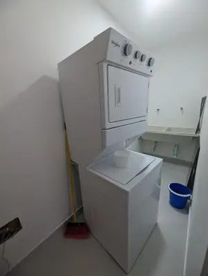 a small white kitchen with a washer and dryer at 2-bedroom apartment with 24h electricity and private parking in Sosúa