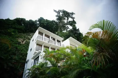 a white building with palm trees in front of it at Yara-ri Apartaments in La Majagua