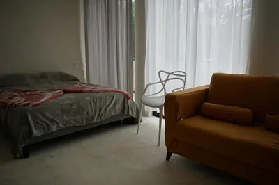 a bedroom with a bed and a chair and a window at Yara-ri Apartaments in La Majagua