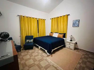a bedroom with a blue bed and yellow curtains at Casa en río san Juan 4 habitaciones in Río San Juan