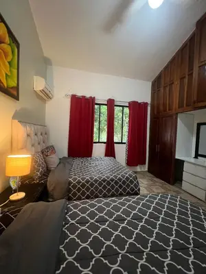 a bedroom with two beds and red curtains at Casa en río san Juan 4 habitaciones in Río San Juan