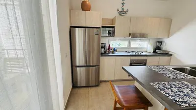 a kitchen with a stainless steel refrigerator and a table at Punta Popy Beach Apartment in Las Terrenas