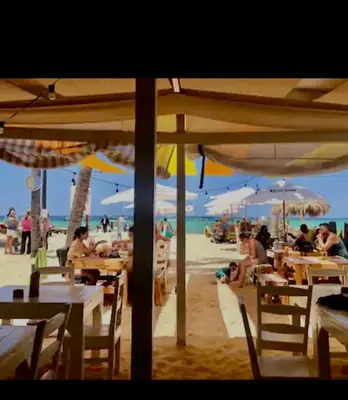 people sitting at tables on the beach under umbrellas at Central in Punta Cana Beach Life RD in Punta Cana